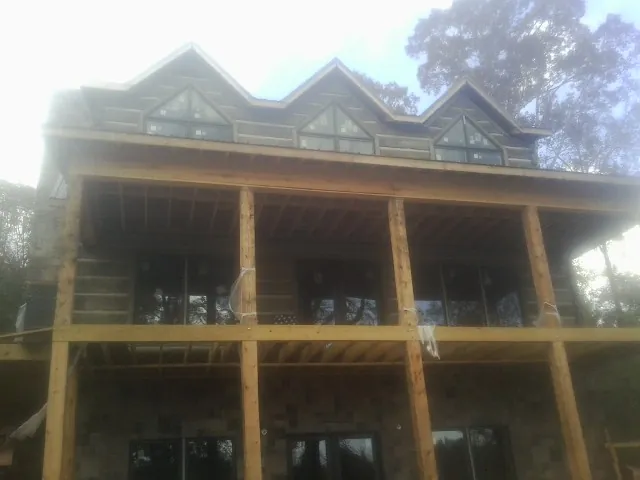 Dormers and porch framing on a large log home under construction — Roof Coating work by our crew in Stillwater